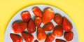 Strawberries in a blue plate on a yellow background. Close-up of fresh strawberries. A top view of a flat layout.