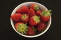 Strawberries in a bowl against a solid black background