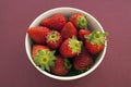 Strawberries in a bowl against a solid magenta background