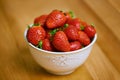 Strawberries, bowl and counter for health, wellness or organic diet on wood countertop. Fruit, nutrition or produce for Royalty Free Stock Photo