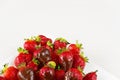 Strawberries dipped in delicious chocolate in white dish isolated on white background. Close up view. Royalty Free Stock Photo