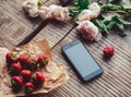Strawberries, flowers and phone on the rustic table. Healthy breakfast, Clean eating, vegan food concept. Royalty Free Stock Photo