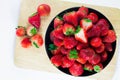 Strawberries fresh in a black cup on a wooden plate with a whit Royalty Free Stock Photo