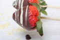 Strawberries glazed in black and white chocolate dries on a plate. On the work surface visible drops of chocolate. Cooking