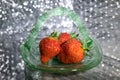 Strawberries in green glass dish with bokeh background