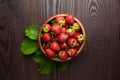 Strawberries with green leaves in wooden bowl on table, top view. Red ripe berries, fresh juicy strawberries on wooden background Royalty Free Stock Photo