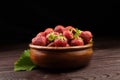 Strawberries with green leaves in wooden bowl on wooden table. Red ripe berries, fresh juicy strawberries on dark background Royalty Free Stock Photo