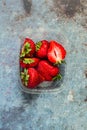 Strawberries in a plastic box on a blue metal background. Eco and Zero Waste Concept Royalty Free Stock Photo
