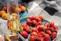 strawberries on plate with glass of champagne or white wine on picnic