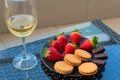 Strawberries and sweets on plate close up with selective focus with glass of champagne or white wine on a table on Royalty Free Stock Photo