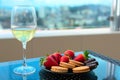 Strawberries and sweets on plate with glass of champagne or white wine on a table on balcony or terrace with blurred Royalty Free Stock Photo