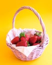 Strawberries in wicker basket on yellow background. Summer harvest. Fresh berries. Royalty Free Stock Photo