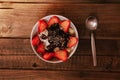 Strawberries with yogurt chocolate pumpkin seeds chia sunflower seeds and apple in a white bowl on a wooden table