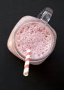 Strawberry banana smoothie in a glass jar mug over black surface, top view. Overhead, flat lay. Close-up Royalty Free Stock Photo