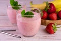 Strawberry and banana smoothie in glasses on a white wooden background. Royalty Free Stock Photo