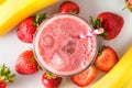 Strawberry and banana smoothie or milkshake in a glass with ice cubes and straw with fresh fruits. top view Royalty Free Stock Photo