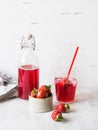 Strawberry beverage in a glass bottle. Cool berry compote in a bottle and glass with straw on white background. Fresh brewed fruit Royalty Free Stock Photo