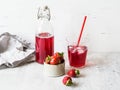 Strawberry beverage in a glass bottle. Cool berry compote in a bottle and glass with straw on a white background. Fresh brewed Royalty Free Stock Photo