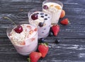 Strawberry, blueberry apricot glass snack homemade organic fresh yogurt delicious oatmeal muesli on a black wooden background