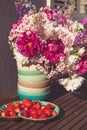 Strawberry and bouquet of pink white and violet flowers