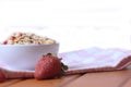 Strawberry and a bowl of muesli on a napkin on wooden table isolated on white background. Horizontal image. Healthy eating concept Royalty Free Stock Photo