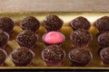 Strawberry Brigadeiro Bicho de pe surrounded by traditional brigadeiros side view