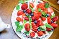 Strawberry cake with blueberries in cream and mint leavesStrawberry cake in cream and mint leaves on the table in a plate