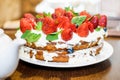 Strawberry cake in cream and mint leaves on the table in a plate