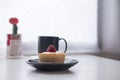 A strawberry cheese tart , a black cup of hot coffee and cactus on white vintage wooden table and curtain background Royalty Free Stock Photo