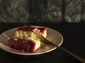 Strawberry cheesecake on a pink plate and a gold fork on a black textured background Royalty Free Stock Photo