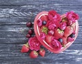 Strawberry, cherry, blueberry natural plate heart, fresh vintage appetizing flower rose on a black wooden background Royalty Free Stock Photo