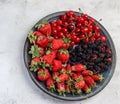 Strawberry, cherry, mulberry on a round plate on a light gray background Royalty Free Stock Photo
