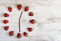 Strawberry clock with arrows of coffee beans, showing twelve hours thirty minutes on a wooden antique table in the kitchen