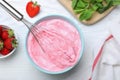 Strawberry cream with balloon whisk on white wooden table, flat lay