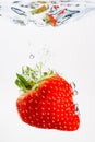 Strawberry falls deeply under water with a big splash. Fruit sinking in clear water on white background Royalty Free Stock Photo