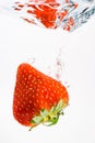 Strawberry falls deeply under water with a big splash. Fruit sinking in clear water on white background Royalty Free Stock Photo