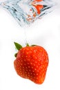 Strawberry falls deeply under water with a big splash. Fruit sinking in clear water on white background Royalty Free Stock Photo