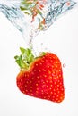 Strawberry falls deeply under water with a big splash. Fruit sinking in clear water on white background Royalty Free Stock Photo