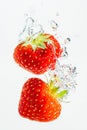 Strawberry falls deeply under water with a big splash. Fruit sinking in clear water on white background