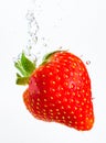 Strawberry falls deeply under water with a big splash. Fruit sinking in clear water on white background Royalty Free Stock Photo