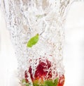 A strawberry falls into a fresh glass of water and makes beautiful bubbles