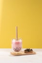 Strawberry flavor boba tea / buble tea with a plate of tapioca ball on yellow background