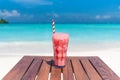 Strawberry Frappuccino cocktail with straw on wooden table ocean background at the beach