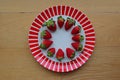 Strawberry fruits arranged in circle around the side of a red stripes plate