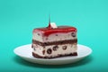 Strawberry glaze drip on piece of vanilla and chocolate layered cake on turquoise background