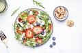 Strawberry and herbs healthy salad with arugula, blueberries, soft white feta cheese and walnuts, white kitchen table, place for Royalty Free Stock Photo