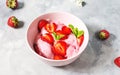 Strawberry ice cream in a bowl with strawberries on a concrete background