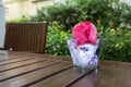 Strawberry ice cream of bright pink in a square plastic cup on a rustic wooden table with a disposable black plastic spoon for ref Royalty Free Stock Photo