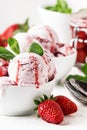 Strawberry ice cream with jam topping, decorated with green mint leaves, gray background, selective focus Royalty Free Stock Photo