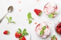 Strawberry ice cream with jam topping, decorated with green mint leaves, gray kitchen table background, top view Royalty Free Stock Photo